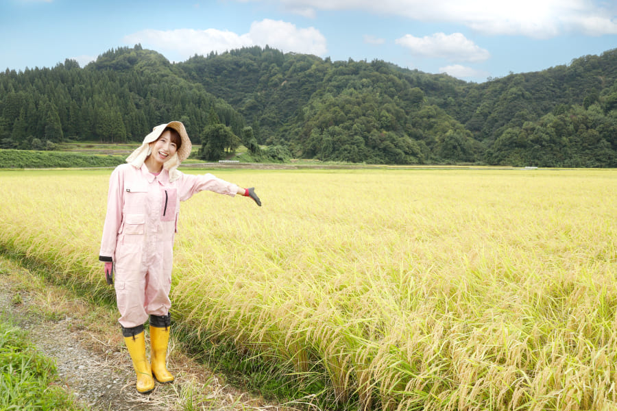 田んぼの前でポーズをとる田中さきさん